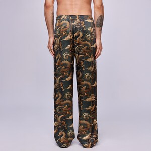 May include: Dark green pants with a repeating pattern of gold dragons and clouds. The pants have a loose, straight leg fit. The fabric has a slight sheen, suggesting a silk or satin material. The overall design has an Asian-inspired aesthetic.