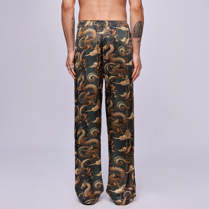 May include: Dark green pants with a repeating pattern of gold dragons and clouds. The pants have a loose, straight leg fit. The fabric has a slight sheen, suggesting a silk or satin material. The overall design has an Asian-inspired aesthetic.