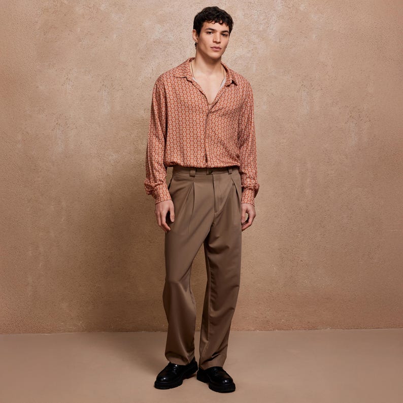 May include: A person wearing a brown patterned long-sleeve shirt with a collared neckline and a pair of brown pants.