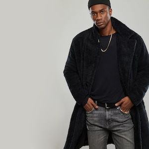May include: A black fuzzy long coat with a black beanie and a gold chain necklace.