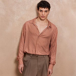 May include: A long-sleeved shirt with a geometric pattern in shades of orange and white. The shirt has a collared neckline and a button-up front.