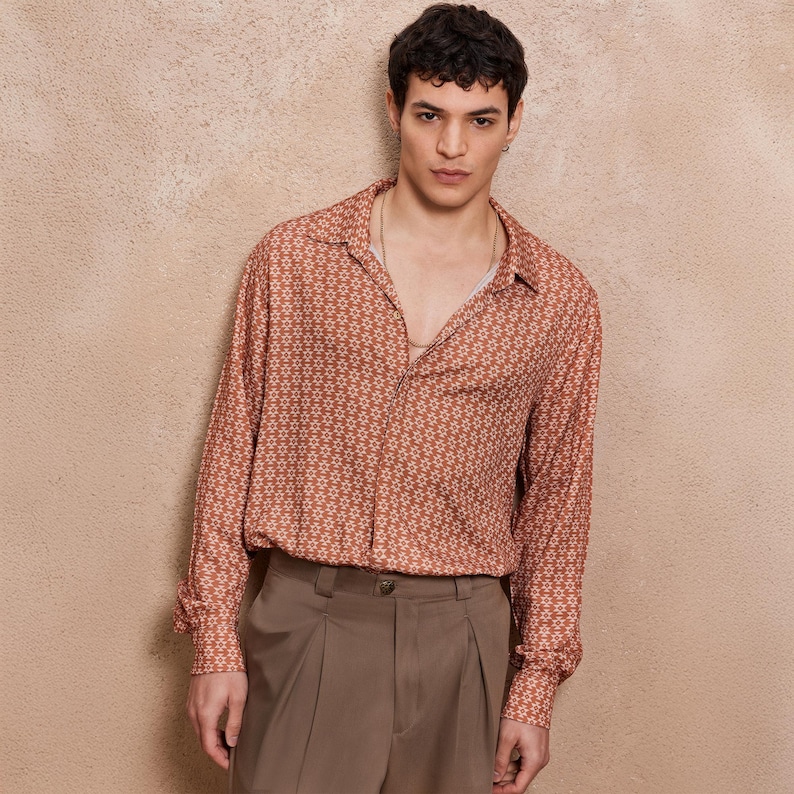 May include: A long-sleeved shirt with a geometric pattern in shades of orange and white. The shirt has a collared neckline and a button-up front.