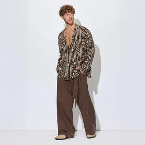 Puede incluir: Una camisa de manga larga con botones y un patrón geométrico en marrón oscuro y beige, combinada con pantalones anchos de color marrón oscuro sólido. La camisa tiene un cuello en V y los pantalones incluyen un detalle de lazo lateral.