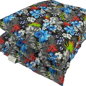 May include: Two stacked square cushions with a tropical floral pattern. The cushions feature a black background with blue, red, white, and green flowers and gray leaves. The cushions are soft and appear to be made of fabric.