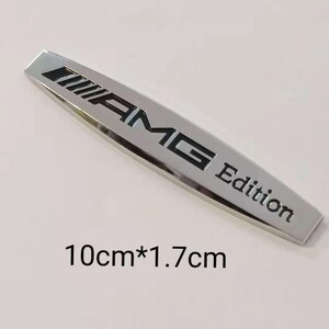 May include: Silver metal car emblem with black lettering that reads "AMG Edition". The emblem is 10 cm by 1.7 cm.