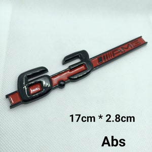 May include: Black and red 6.3 AMG emblem with a black background and red lettering. The emblem is 17 cm by 2.8 cm and is made of ABS plastic.