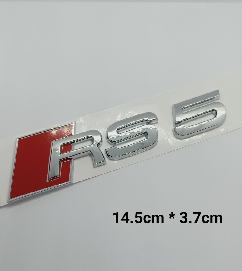 K&ouml;nnte beinhalten: Ein Chrom-RS 5-Emblem mit rotem Hintergrund. Das Emblem ist 14,5 cm x 3,7 cm gro&szlig;.
