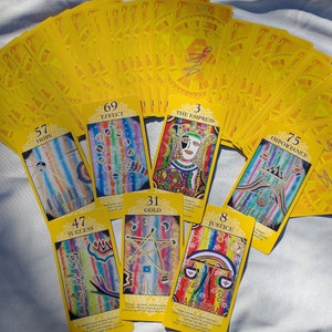 Puede incluir: Un despliegue de cartas de tarot coloridas con dorso amarillo. Las cartas muestran números y palabras como "Hope", "Effect", "The Empress", "Importance", "Success", "Gold", y "Justice".