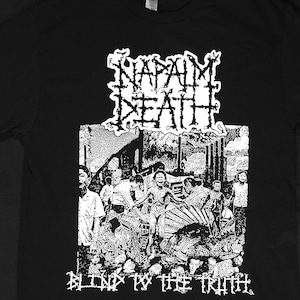 Puede incluir: Camiseta negra con un gráfico blanco de la banda Napalm Death. El gráfico incluye el nombre de la banda en una fuente de alambre de púas y las palabras "Blind To The Truth" debajo. El gráfico también presenta una imagen en blanco y negro de una escena de destrucción.
