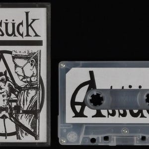 Può includere: Un nastro audio in bianco e nero con la parola "Assück" stampata sul davanti. Il nastro è in una custodia di plastica trasparente.