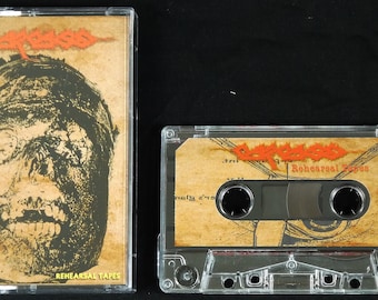 May include: A cassette tape with a black and white image of a face on the cover. The tape is labeled "Gorefeast" and "Rehearsal Tapes".