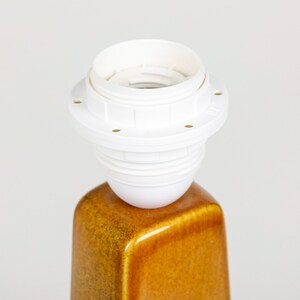 May include: White ceramic lamp socket with a gold ceramic base.