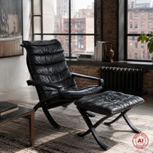Op de afbeelding: Een zwarte leren fauteuil met bijpassende voetenbank, voorzien van een gecapitonneerde, gesegmenteerde rugleuning en zitting. De stoel heeft gebogen houten armleuningen en een donker frame, wat zorgt voor een gestructureerde, achteroverleunende zithouding.