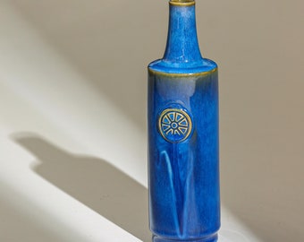 May include: A blue ceramic vase with a gold design. The vase has a narrow neck and a wide base.