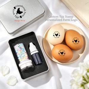 May include: A custom egg stamp set with a personalized farm logo. The set includes a stamp, ink, and a container of colourful ink pads. Three eggs are stamped with the farm logo. The text on the stamp reads "Glazebrook Farm Fresh Eggs".