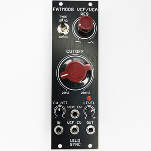 Puede incluir: M&oacute;dulo electr&oacute;nico negro con perillas rojas y texto blanco. El m&oacute;dulo tiene el texto "FATMOOG UCF/UCA" en la parte superior y "WILD SYNC" en la parte inferior. Cuenta con un interruptor de palanca, m&uacute;ltiples conectores de entrada y una perilla de corte grande.