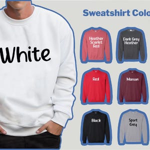 May include: A white sweatshirt with the word "White" in large, black letters. The image also displays a color chart with various sweatshirt colors, including red, black, and green. The sweatshirt is part of the Double Mood Collection.