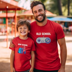 Op de afbeelding: Twee mensen dragen bijpassende rode t-shirts. Op &eacute;&eacute;n shirt staat "OLD SCHOOL" met een controller-afbeelding. Op het andere shirt staat "NEW SCHOOL" met een gamecontroller-afbeelding. Beide mensen lachen.