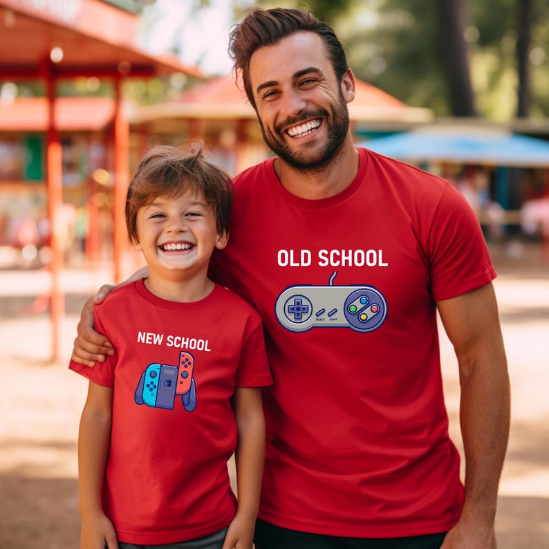 Op de afbeelding: Twee mensen dragen bijpassende rode t-shirts. Op &eacute;&eacute;n shirt staat "OLD SCHOOL" met een controller-afbeelding. Op het andere shirt staat "NEW SCHOOL" met een gamecontroller-afbeelding. Beide mensen lachen.