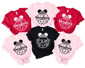 May include: Six pink, red, and black t-shirts with a Disney World theme. The shirts feature a Mickey Mouse head with the iconic Spaceship Earth logo inside. The text on the shirts reads "Disney Drinking Team" and "It's My 21st".