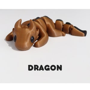 May include: A brown 3D printed dragon figurine with black eyes. The figurine is lying on its belly with its head resting on the ground. The text "DRAGON" is printed below the figurine.