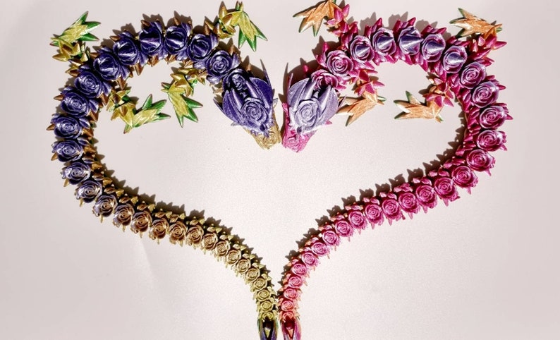 Peut inclure: Une forme de c&oelig;ur r&eacute;alis&eacute;e avec des fleurs en tissu de couleur violette, rose, dor&eacute;e et verte. Les fleurs sont dispos&eacute;es en d&eacute;grad&eacute;, les fleurs violettes en haut et les fleurs vertes en bas.