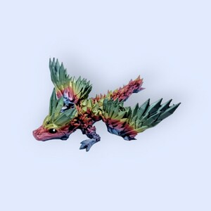 May include: A small, rainbow-colored dragon figurine with green wings and a spiky back. The dragon is made of plastic and has a detailed design.