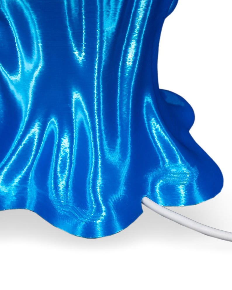May include: A blue 3D printed lamp with a wavy, textured surface and a white cord.