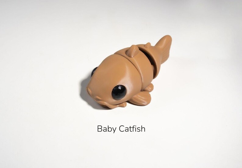 May include: A brown, cartoon-style catfish figurine with large black eyes. The figurine is made of plastic and has a segmented body.