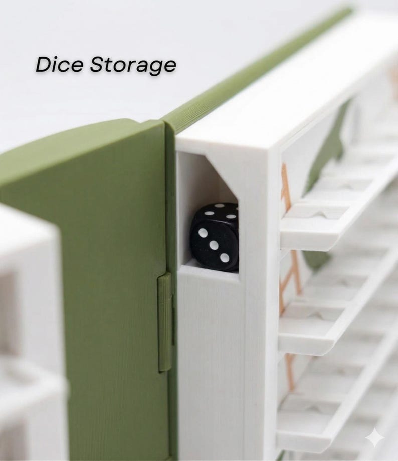 May include: A close-up of a dice storage box. The box is white and olive green with the words "Dice Storage" printed on the top left. A black die with white dots is visible inside the box.
