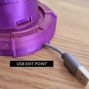 May include: A purple 3D printed base with a USB cable exiting from the side. The text "USB EXIT POINT" is printed on the base.
