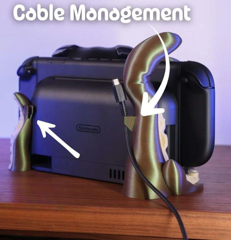 May include: A cable management system for a Nintendo Switch. The system is designed to look like an octopus, with a gold-colored tentacle holding the charging cable. The words "Cable Management" are at the top of the image.