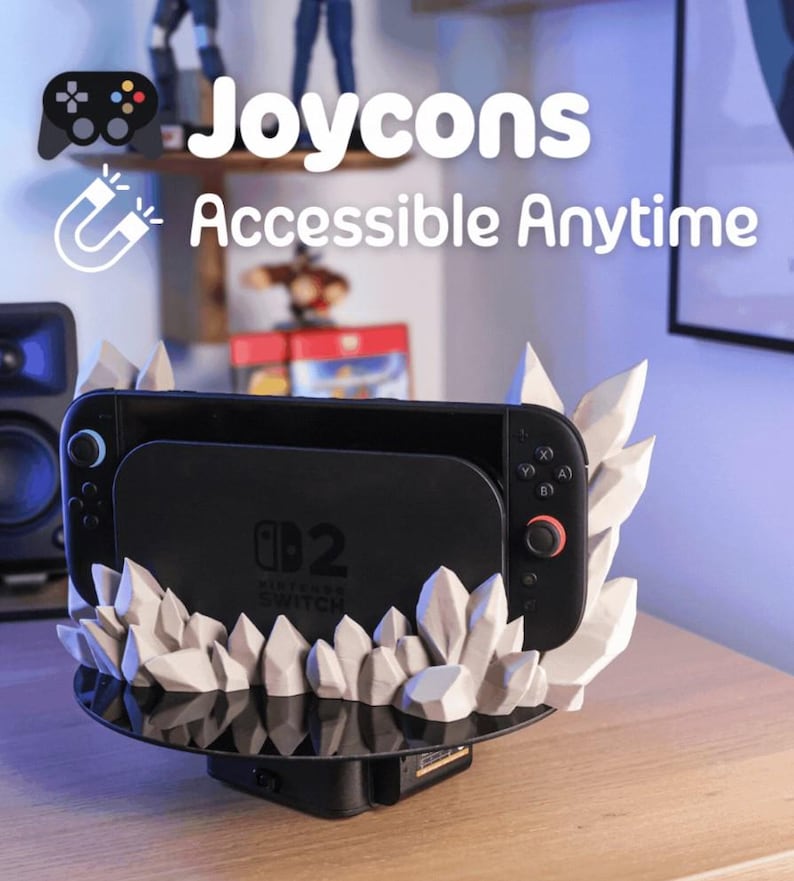 May include: A black Nintendo Switch console is docked in a custom stand. The stand features a black base and is decorated with white, crystal-like structures. The text "Joycons Accessible Anytime" is displayed above the console.