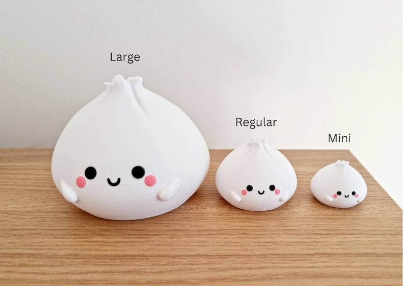 May include: Three white ceramic figurines shaped like steamed buns with cute faces. The figurines are labeled "Large", "Regular", and "Mini" from left to right.