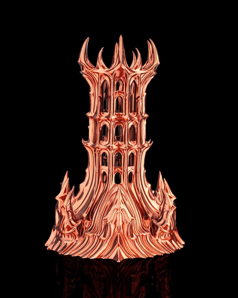 May include: A copper-colored, ornate tower sculpture with a detailed, multi-tiered design. The tower features arched windows and a spiked crown, set against a black background. The metallic finish reflects light, highlighting the intricate architectural details.