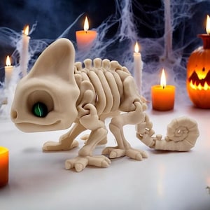May include: A white skeletal chameleon figurine with green eyes, surrounded by lit candles and a jack-o'-lantern. The figurine is posed in a walking position with its tail curled.
