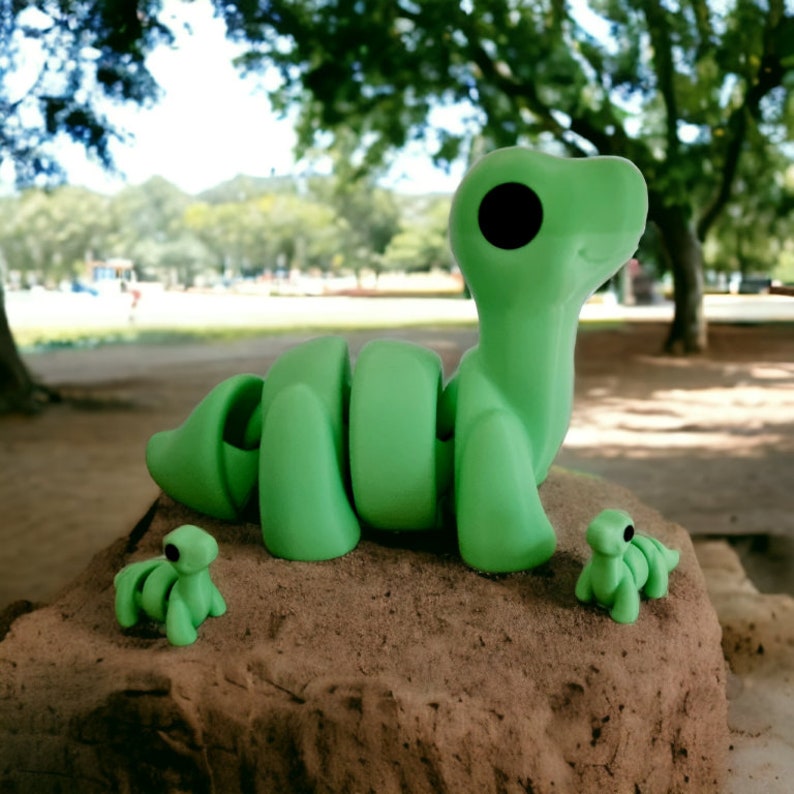 Pu&ograve; includere: Tre bruchi di plastica verde, uno grande e due piccoli, su una superficie di sabbia marrone. Il bruco grande &egrave; arrotolato con la testa alzata. I bruchi pi&ugrave; piccoli sono rivolti verso lo spettatore.