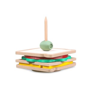 May include: A wooden toy sandwich with layers of bread, tomato, lettuce, and cheese. A wooden toothpick with a green olive sits atop the sandwich. The toy is designed for children.