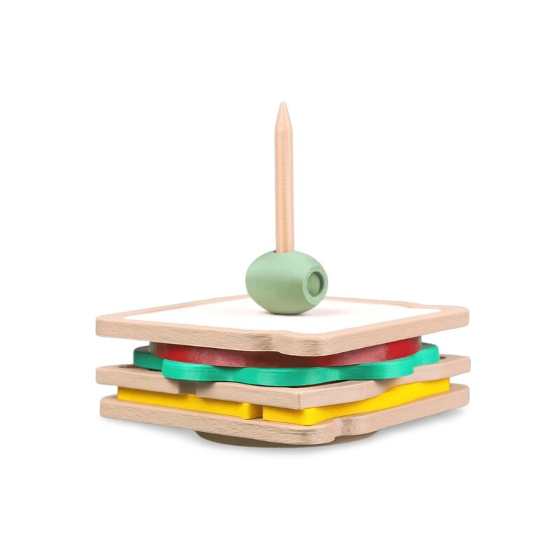 May include: A wooden toy sandwich with layers of bread, tomato, lettuce, and cheese. A wooden toothpick with a green olive sits atop the sandwich. The toy is designed for children.
