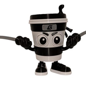 May include: A black and white coffee cup figurine with cartoon eyes, a ninja headband, and two gray swords. The cup has black sneakers and arms. The design is a playful take on a ninja theme.