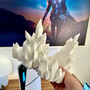 May include: White 3D printed crystal rock formation. The rock formation is made of many individual crystals that are all connected together. The crystals are all different sizes and shapes.