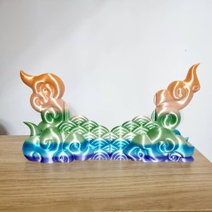 May include: A 3D printed decorative object with a rainbow gradient color scheme. The object is shaped like a cloud with a wave pattern. It is made of plastic and has a smooth, glossy finish.