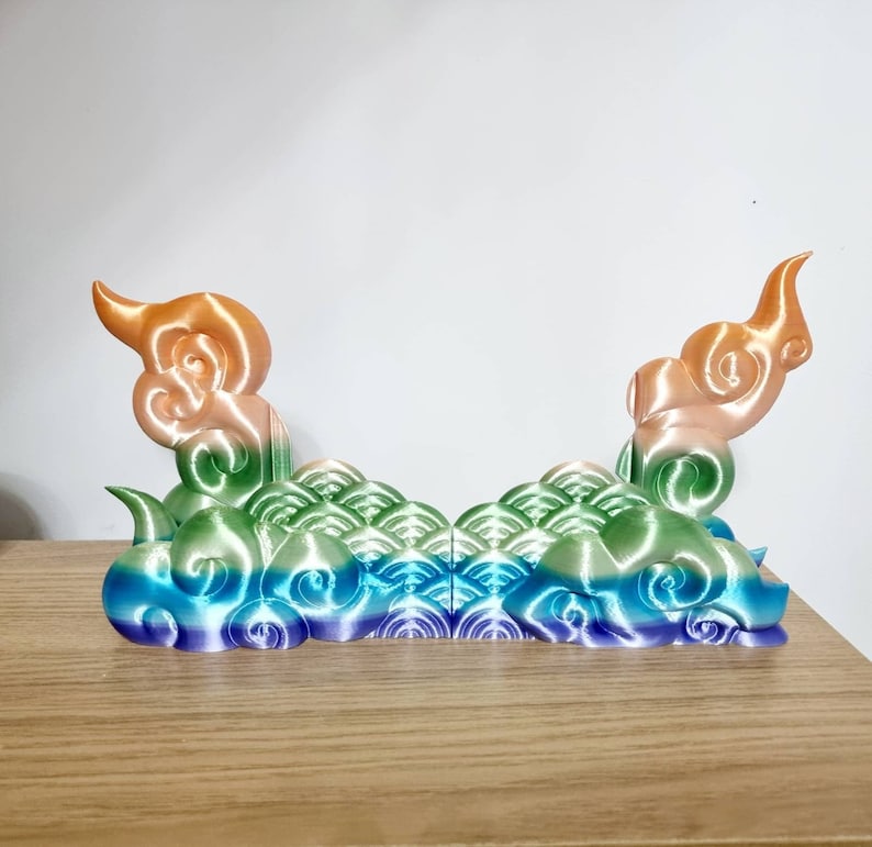 May include: A 3D printed decorative object with a rainbow gradient color scheme. The object is shaped like a cloud with a wave pattern. It is made of plastic and has a smooth, glossy finish.