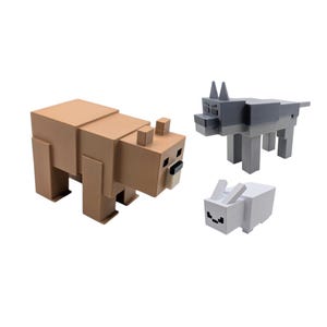 May include: Three block-style animal figures: a tan bear, a grey wolf, and a white rabbit. The bear is the largest, with a rectangular body and blocky limbs. The wolf and rabbit are smaller, with similar geometric designs.
