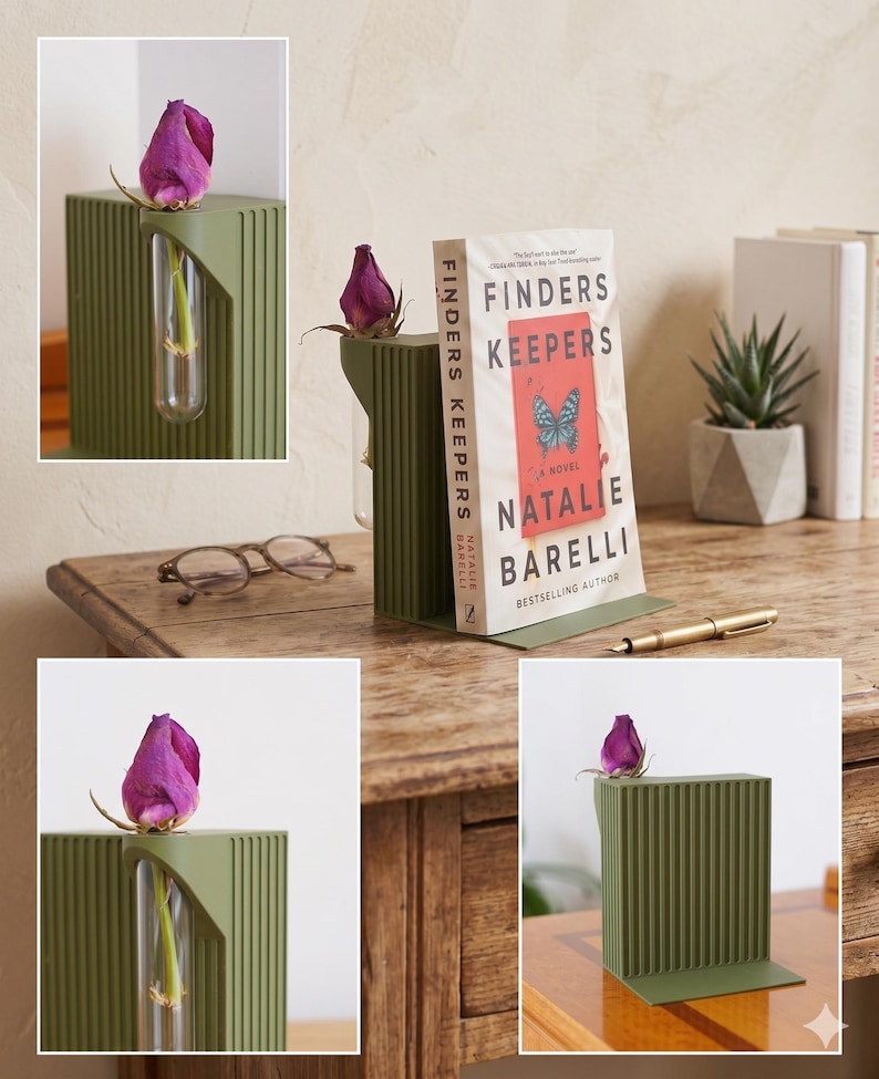 May include: A sage green metal bookend with a vertical ribbed design, holding a book titled "Finders Keepers" by Natalie Barelli. A small glass vial holds a single purple rose bud. A gold pen rests nearby.