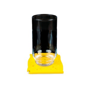 May include: A clear glass tumbler with a black top sits on a yellow, cheese-shaped coaster. The coaster has several small, circular cutouts. The glass is empty and reflects the light.