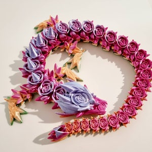 Peut inclure: Un dragon floral en argile polym&egrave;re de couleur violet et rose. Le dragon est enroul&eacute; en cercle avec sa queue dans sa bouche. Le dragon est d&eacute;cor&eacute; de petites fleurs d&eacute;licates.