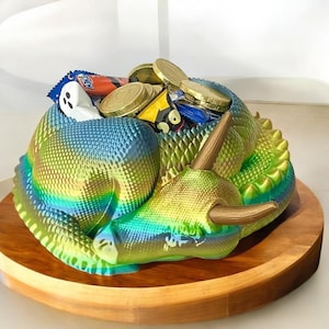 May include: A green, blue, and gold iridescent dinosaur-shaped bowl filled with candy and coins. The bowl is sitting on a wooden base.