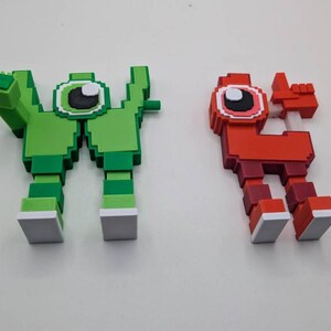 May include: Two pixelated figures, one green and one red, stand side-by-side. The green figure has a large eye and outstretched arm. The red figure has a similar design, with a raised hand. Both figures have white-tipped feet.