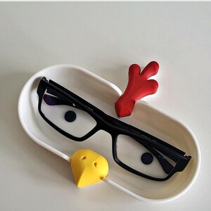 May include: White ceramic glasses holder shaped like a chicken with a red comb, yellow beak, and black glasses resting inside.